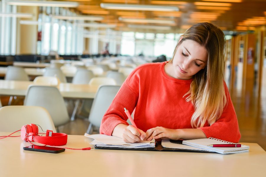 garota estudando para o vestibular em uma biblioteca depois de fazer uma rotina de estudos