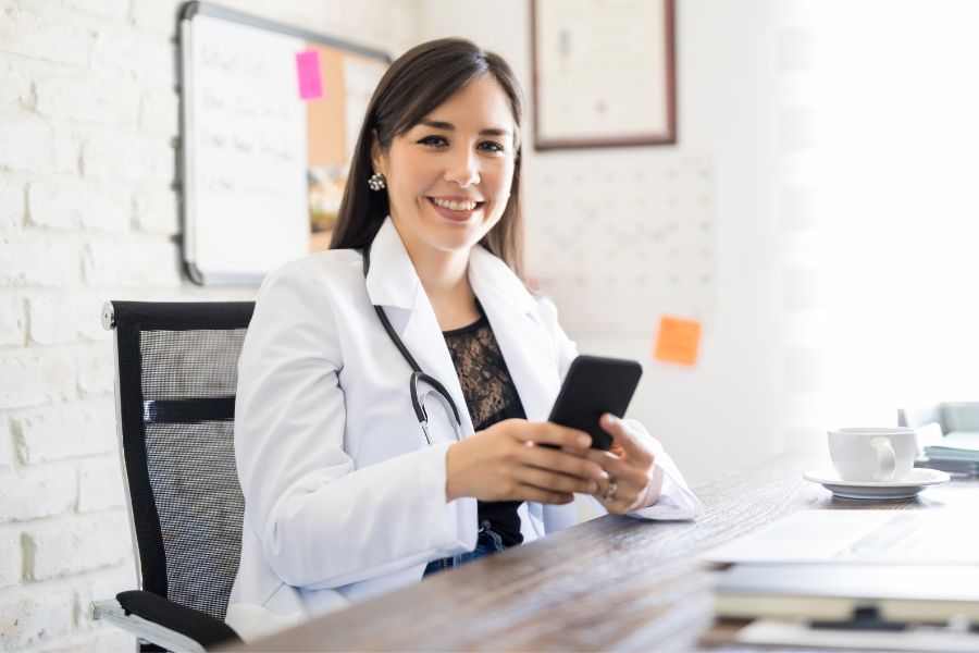 Médica usando celular para publicar nas redes sociais seguindo ética médica